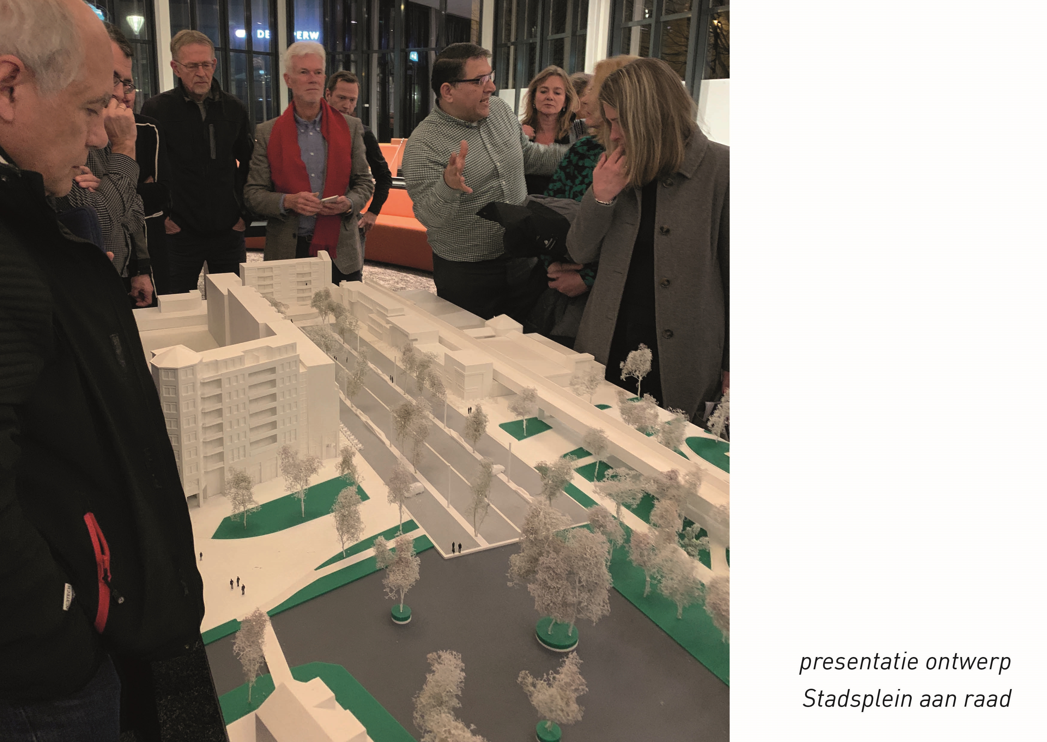 Foto van de presentatie van het ontwerp Stadsplein aan de raad. Raadsleden staan om een maquette heen.